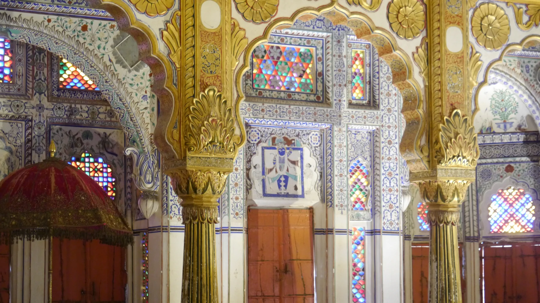 Gold-painted columns and stained-glass windows inside Phool Mahal at Mehrangarh Fort.